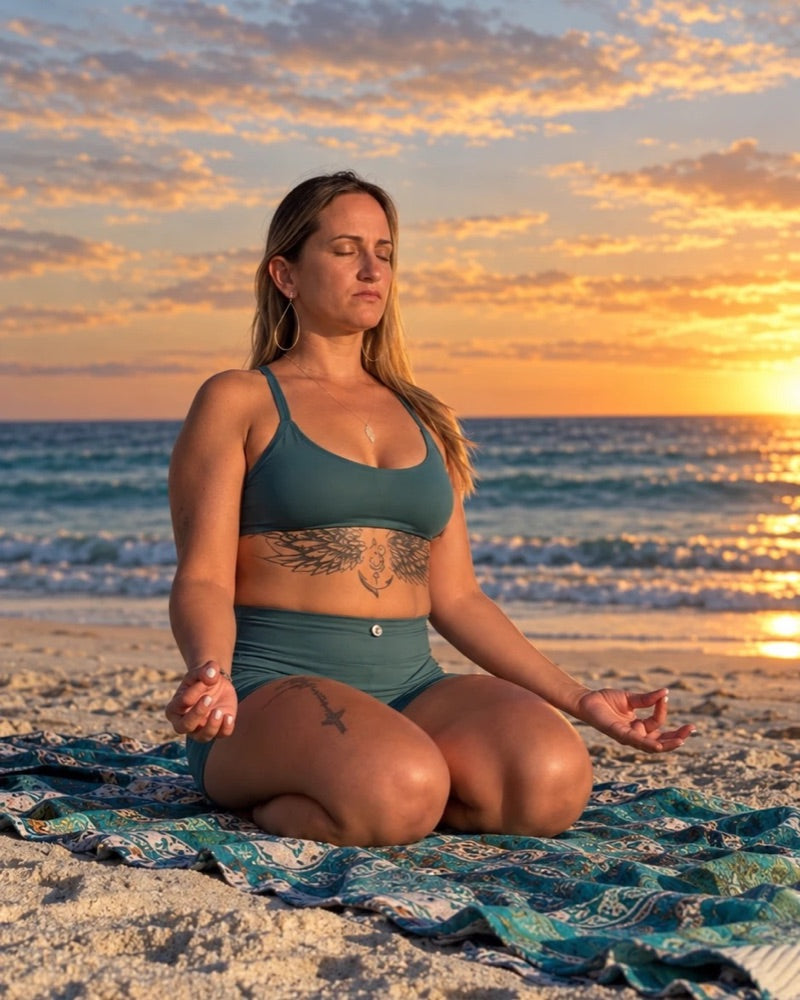 Meghan Escobar meditating on the beach at sunset