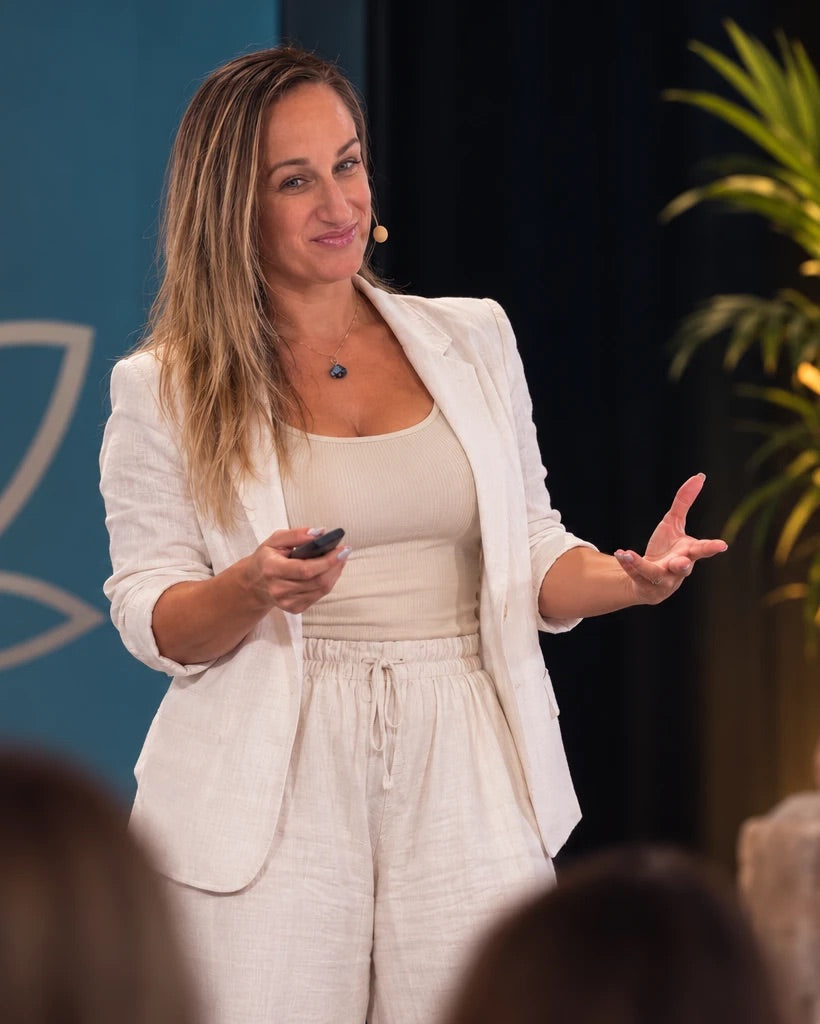 Meghan Escobar speaking on stage at a wellness event